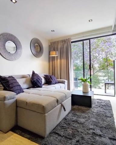 Apartment living room with floor-to-ceiling windows and jacaranda tree view