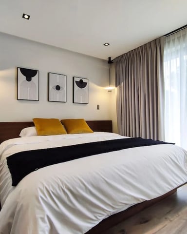 Light-filled apartment bedroom with sheer curtains and large windows